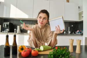portrait-woman-checking-grocery-list-looking-vegetables-holding-notebook-reading-recipe-while_1258-193238